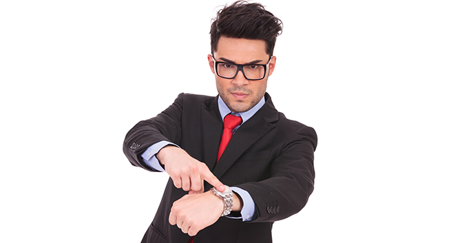 young business man pointing angrily to his watch and looking at the camera, on a white background